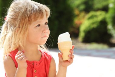 Parkın doğasında dondurma yiyen mutlu çocuk.