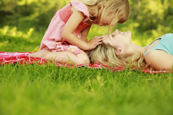 Happy mother with baby in nature lying on the grass in the park — Stock Photo, Image