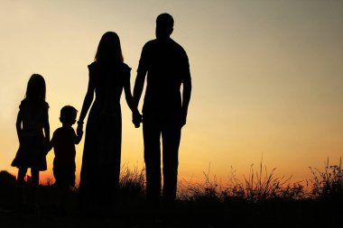 Günbatımında niteliğine mutlu bir aile silüeti 