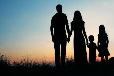 Günbatımında niteliğine mutlu bir aile silüeti 