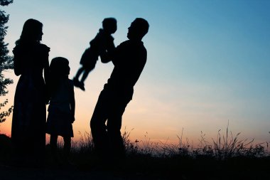 Günbatımında niteliğine mutlu bir aile silüeti 