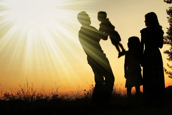 Silhueta de uma família feliz sobre a natureza do pôr do sol no — Fotografia de Stock