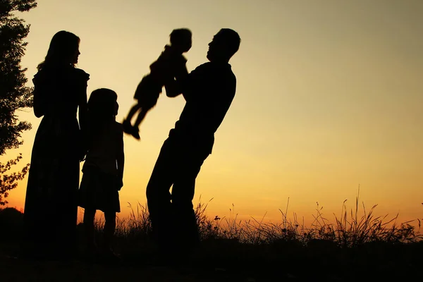 silhouette of a happy family on the nature of the sunset in the
