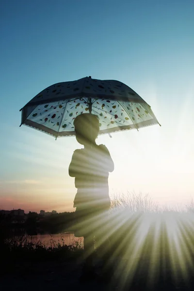 Happy child with an umbrella silhouette on nature in the park su — Stock Photo, Image