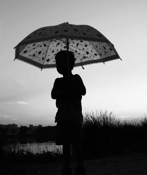 Szczęśliwe dziecko z sylwetka parasol na charakter w park su — Zdjęcie stockowe