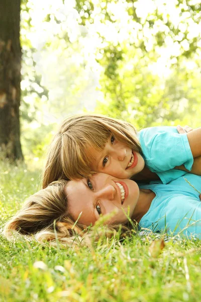 Child with mother play outdoors in a park on the mother in the g — Stock Photo, Image