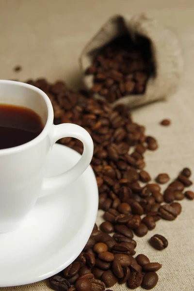 Piękna filiżanka kawy z ziarna i torba na tle — Zdjęcie stockowe