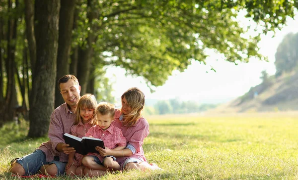 Família jovem lendo a Bíblia na natureza — Fotografia de Stock