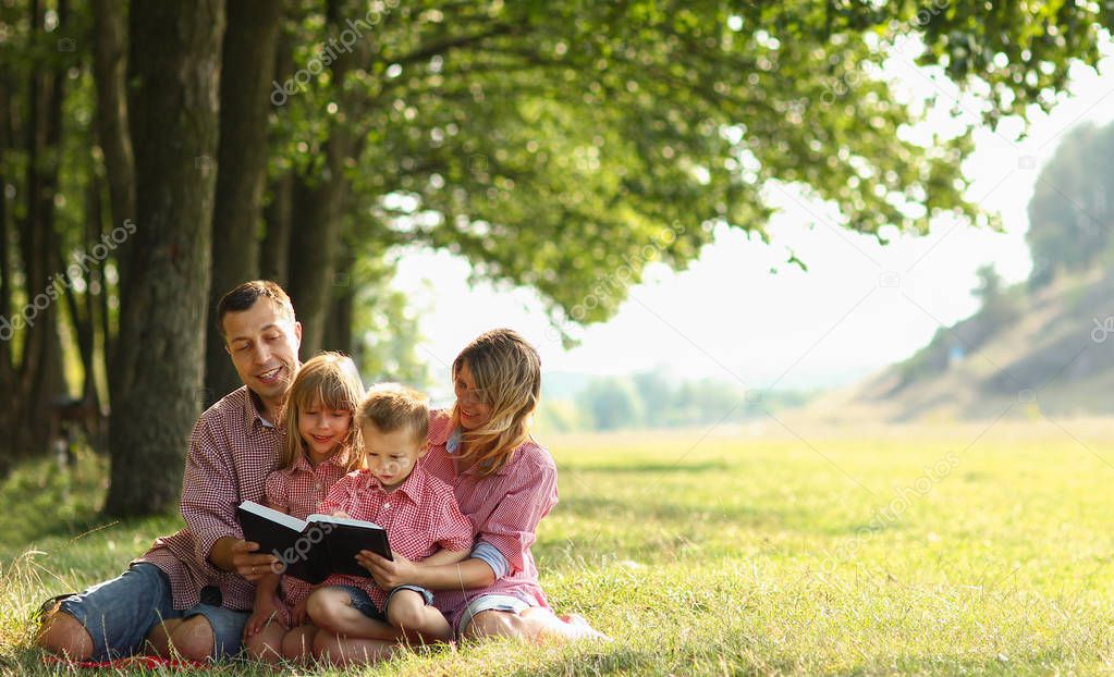 Young family reading the Bible in nature