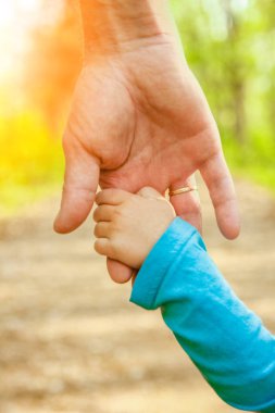 Mutlu bir geçmişi olan çocuğun elini tutan ebeveyn.