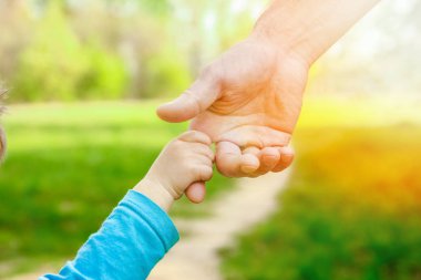 Mutlu bir geçmişi olan çocuğun elini tutan ebeveyn.