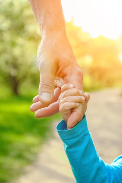 Il genitore che tiene la mano del bambino con uno sfondo felice — Foto Stock