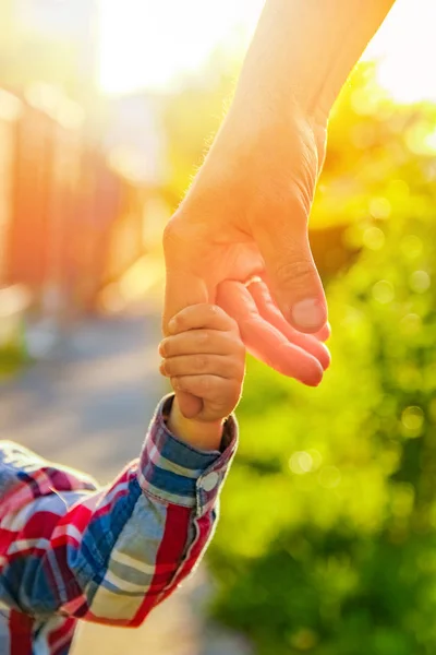 De ouder die de hand van het kind met een gelukkige achtergrond vasthoudt — Stockfoto