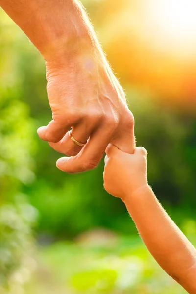 Ο γονέας κρατώντας το χέρι του παιδιού με ένα ευτυχισμένο υπόβαθρο — Φωτογραφία Αρχείου