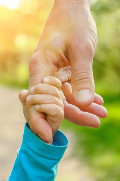 De ouder die de hand van het kind met een gelukkige achtergrond vasthoudt — Stockfoto