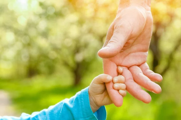 De ouder die de hand van het kind met een gelukkige achtergrond vasthoudt — Stockfoto