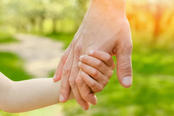 Der Elternteil hält die Hand des Kindes mit einem glücklichen Hintergrund — Stockfoto