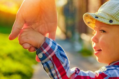 Mutlu bir geçmişi olan çocuğun elini tutan ebeveyn.
