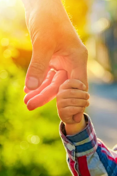 De ouder die de hand van het kind met een gelukkige achtergrond vasthoudt — Stockfoto