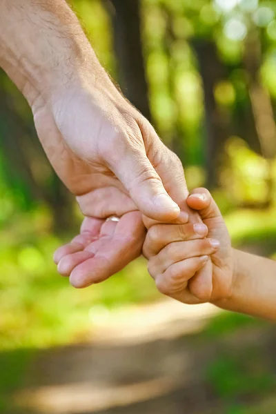 Il genitore che tiene la mano del bambino con uno sfondo felice — Foto Stock