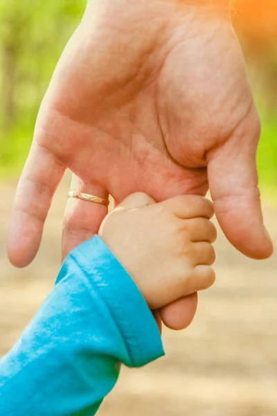 A szülő boldog háttérrel fogja a gyermek kezét — Stock Fotó