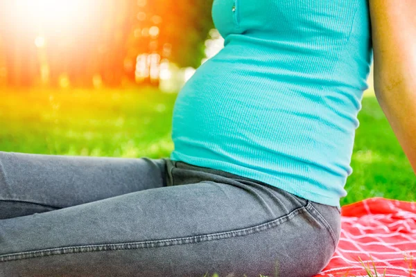 Happy pregnant woman with a guy in a park on the nature backgrou — Stock Photo, Image