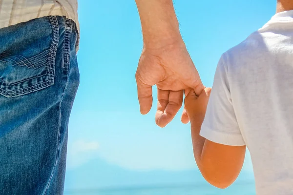 Feliz papá toma la mano de un niño por el mar griego en la naturaleza —  Fotos de Stock