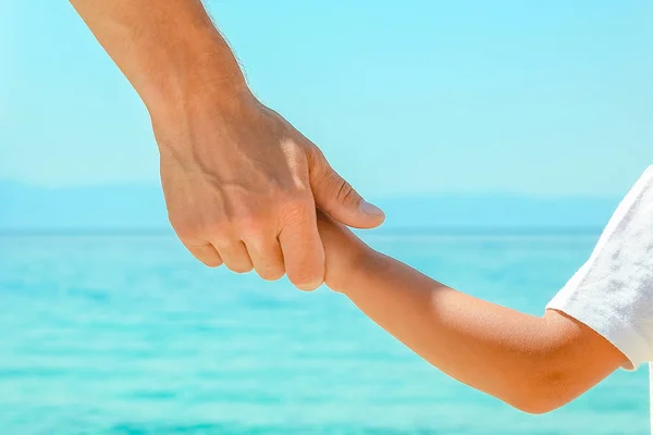 Šťastný táta drží ruku dítěte u řeckého moře v přírodě — Stock fotografie