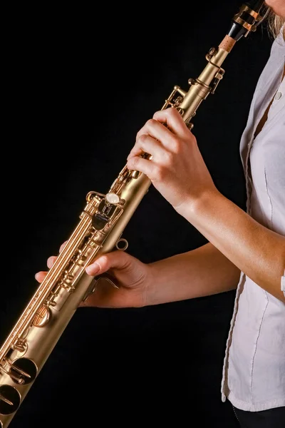 Saxofón soprano en manos de una chica sobre un fondo negro — Foto de Stock