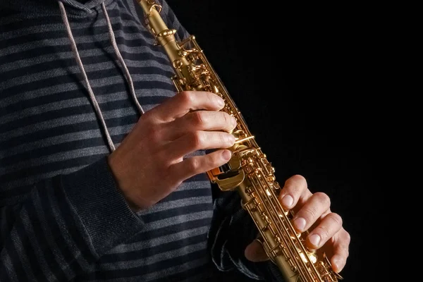 Saksofon sopranowy w rękach faceta na czarnym tle — Zdjęcie stockowe