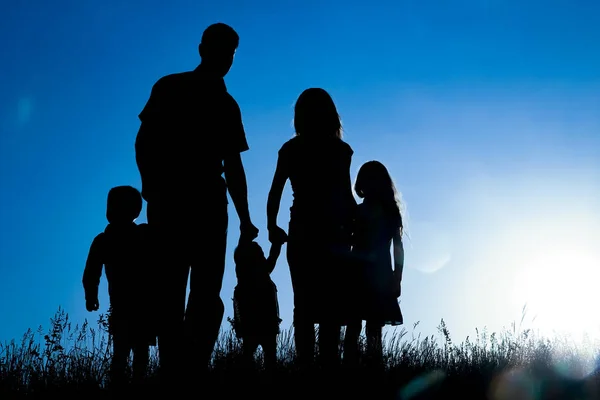 Família feliz ao ar livre na silhueta do parque — Fotografia de Stock