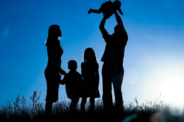 Gelukkige familie buitenshuis in het Park silhouet — Stockfoto