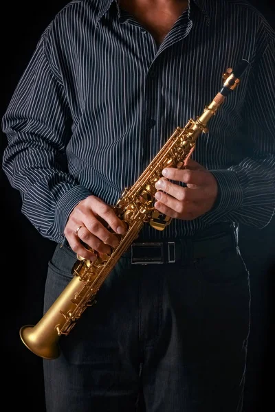 Saxofón soprano en las manos de un chico sobre un fondo negro — Foto de Stock