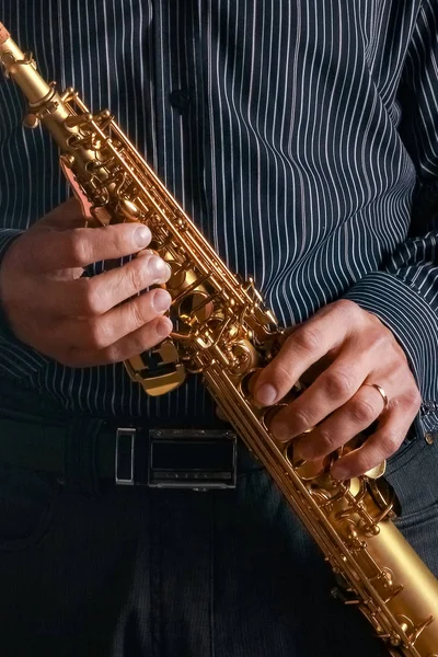 Saxofón soprano en las manos de un chico sobre un fondo negro — Foto de Stock