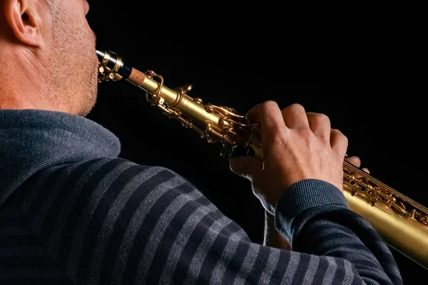 Saxofón soprano en las manos de un chico sobre un fondo negro — Foto de Stock