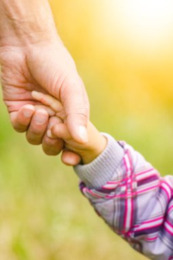 Mutlu aile ve çocuk parkta el ele tutuşuyor.