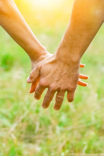 Handen van een gelukkig koppel in de buitenlucht in het zomerpark — Stockfoto