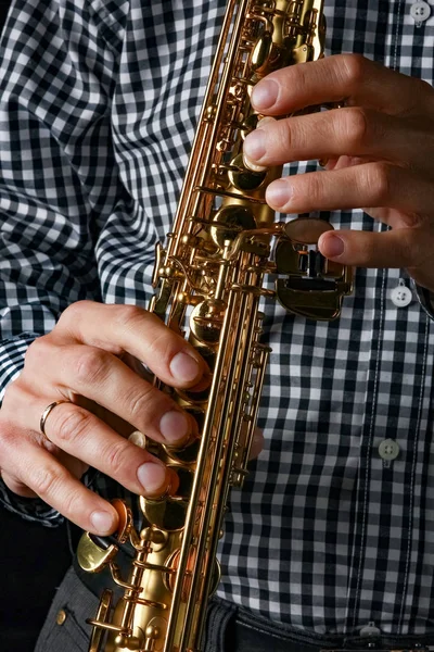 Saxofón soprano en manos sobre fondo negro — Foto de Stock
