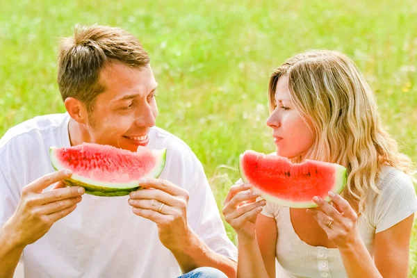 Szczęśliwy para w miłość jedzenie arbuz na zewnątrz w letnim parku — Zdjęcie stockowe