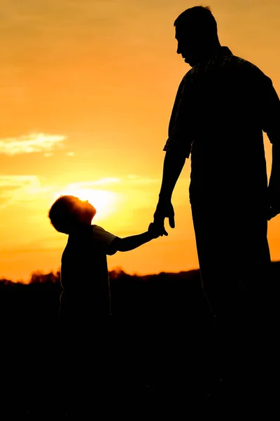 Gelukkig vader met een kind in het park buiten silhouet — Stockfoto