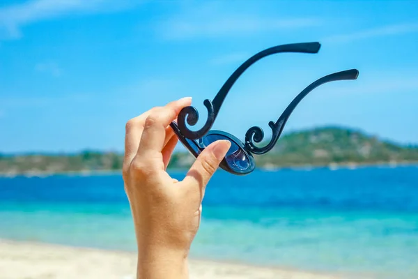 Belas mãos com óculos de sol junto ao mar no fundo da natureza — Fotografia de Stock