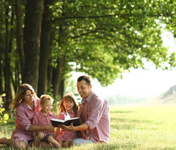 Familia joven leyendo la Biblia en la naturaleza — Foto de Stock