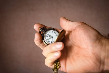 Bir adamın elinde bir cep saati.