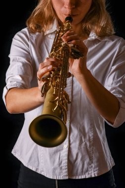 soprano saxophone in the hands of a girl on a black background clipart