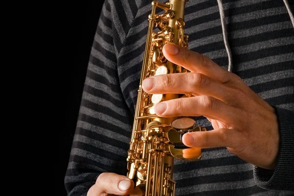 Soprano saxofone nas mãos de um cara em um fundo preto — Fotografia de Stock