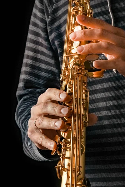 Saxofón soprano en las manos de un chico sobre un fondo negro — Foto de Stock