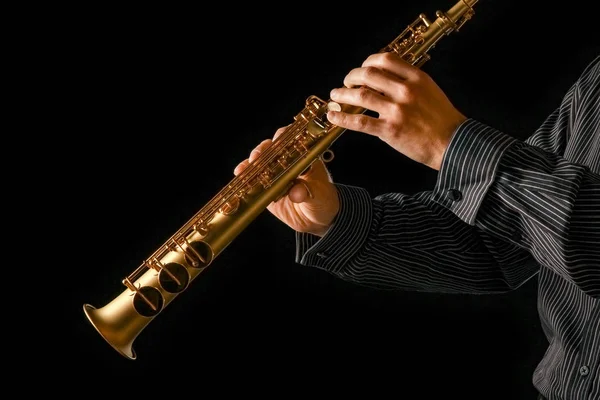 Soprán saxofon v rukou na černém pozadí — Stock fotografie