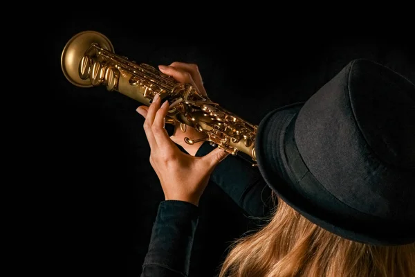Soprano saxofone nas mãos de uma menina em um fundo preto — Fotografia de Stock