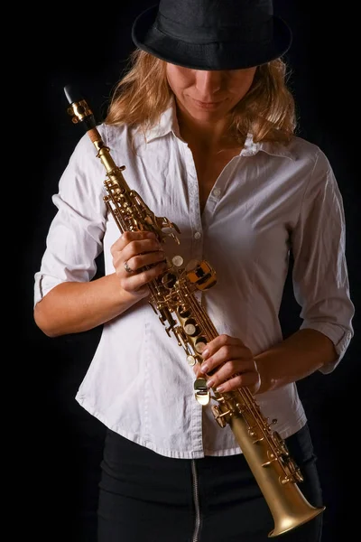 Soprano saxofone nas mãos de uma menina em um fundo preto — Fotografia de Stock