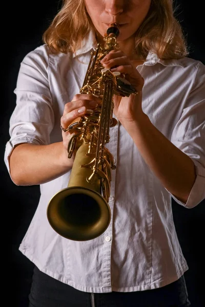 Soprano saxofone nas mãos de uma menina em um fundo preto — Fotografia de Stock